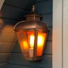 Wandlamp koper met bronzen vlam bovenop hangend aan een saunahuisje.